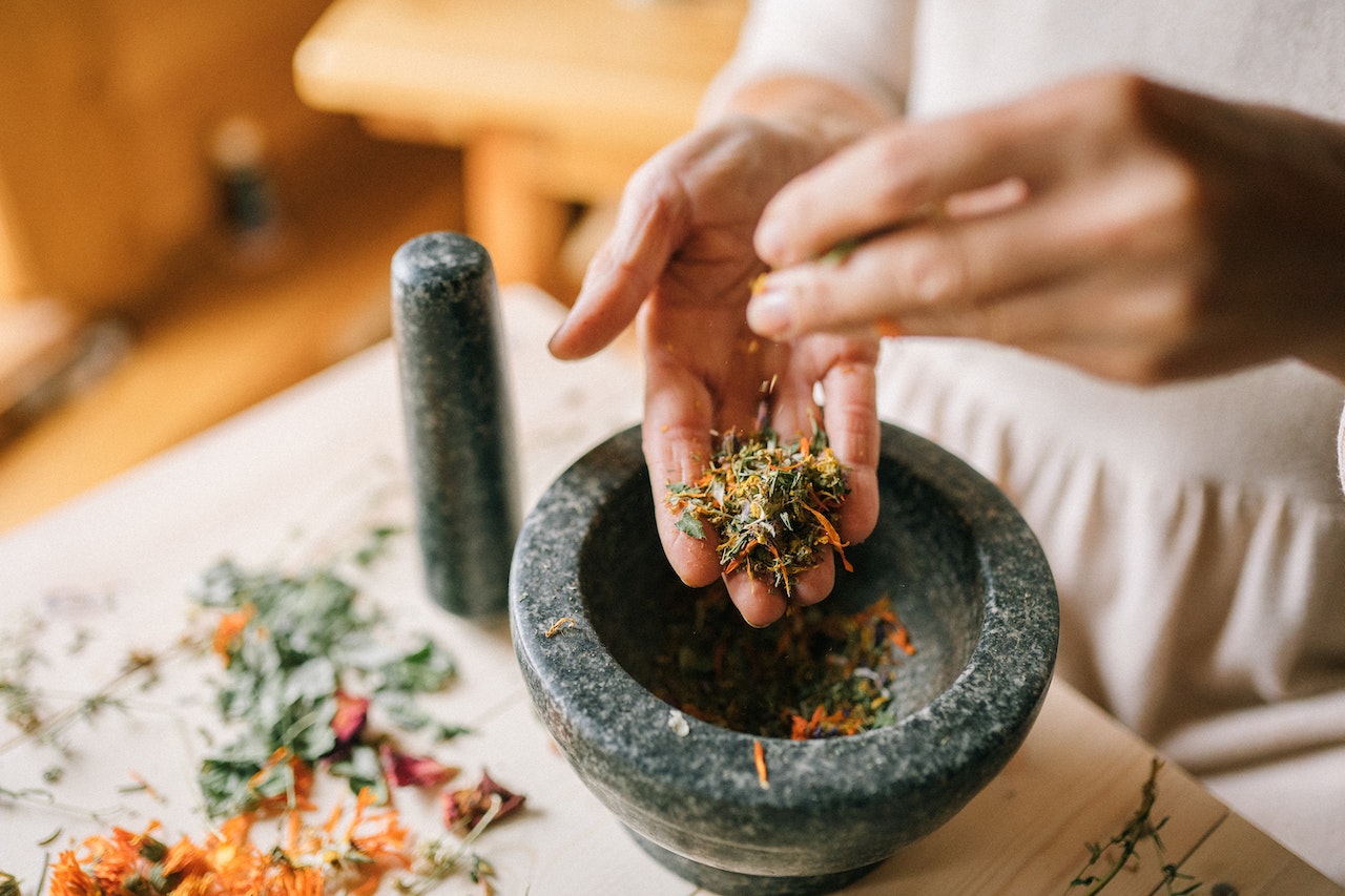 Woman Preparing Chinese Herbs in Pounder